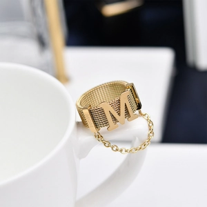 Macro detail of gold mesh ring with letter M and MOM engraving on coffee cup handle