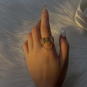 Detailed macro of golden mesh ring with M letter charm and delicate hanging chain