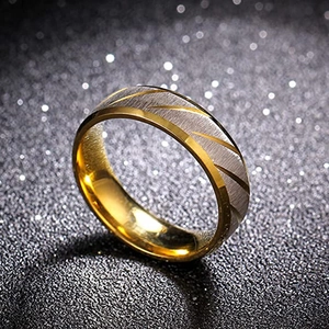 Détail macro d'une bague en acier brossé avec finition bicolore or et rainures obliques