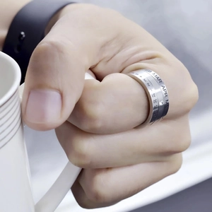 Rotating stainless steel calendar spinner ring with engraved months and dates on thumb