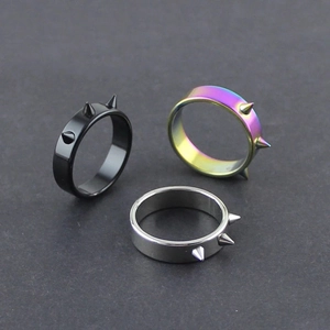 Dettaglio macro di anelli gotici con punte in finiture nero, argento e arcobaleno