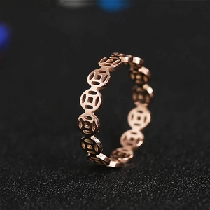 Vintage rose gold stainless steel hollow coin ring with traditional pattern on black background