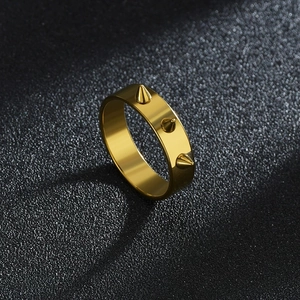 Vista macro di un anello in titanio dorato lucido con tre rivetti a punta punk