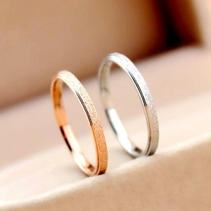 Vue macro de bagues en acier inoxydable givré or rose et argent dans un écrin à bijoux