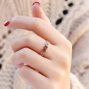 Macro shot of rose gold copper coin pattern ring on finger with red nail polish