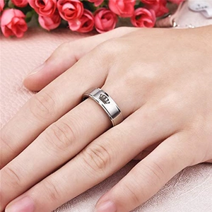 Detail eines silbernen Kronenrings an der Hand mit romantischem Rosenhintergrund