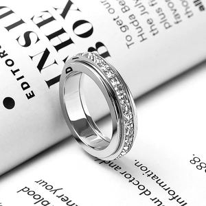 Primer plano de anillo giratorio de acero titanio plateado con circonitas de corte princesa