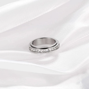 Vista de cerca del anillo giratorio de plata con circonitas sobre satén blanco