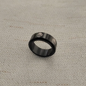 Macro detail of 8mm black stainless steel rotating ring with yin yang tai chi patterns