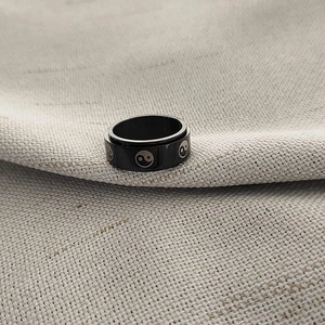 Detailed close-up of a rotating black stainless steel spinning ring with Yin Yang patterns