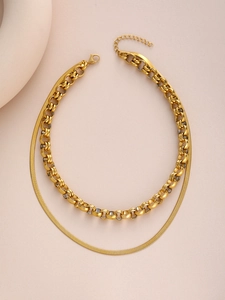 Close-up of gold double-layer necklace featuring rolo and snake chain links with lobster clasp