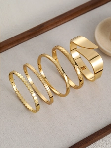 Dettaglio di cinque bracciali in acciaio inossidabile placcati oro 18k in varie texture
