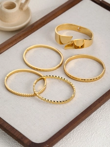 Dettaglio di 5 bracciali in acciaio inossidabile placcato oro con motivi testurizzati