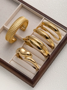 Détail macro de cinq bracelets joncs dorés présentés dans un écrin à bijoux de luxe