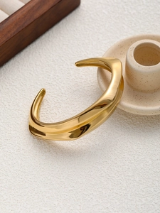 Vue détaillée d'un bracelet jonc doré ondulé avec une finition métallique très polie