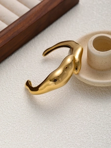 Macro d'un large bracelet doré avec un design sculptural organique et irrégulier