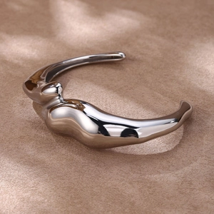 Gros plan sur un large bracelet jonc ouvert argenté avec surface polie miroir