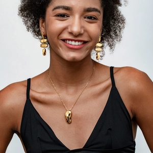 Gros plan sur un ensemble boucles d'oreilles et collier dorés portés par un mannequin