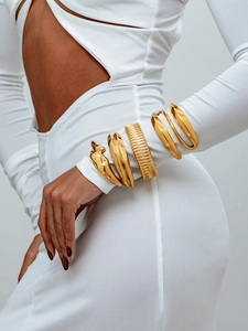 Détail de larges bracelets empilés en acier titane doré poli sur le poignet