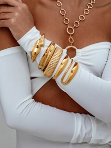 Bracelets manchettes en or poli et collier à maillons portés par un mannequin
