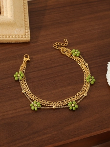 Detailed view of layered 18k gold plated flower bracelet on rustic brown wooden surface