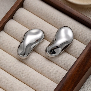 Boucles d'oreilles cacahuète en métal liquide argenté dans un écrin à bijoux en bois