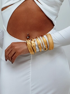 Détail de bracelets larges en acier doré avec finitions lisses et texturées