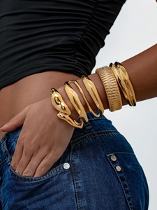 Détail d'un lot de cinq bracelets dorés polis avec tête de serpent et anneaux larges