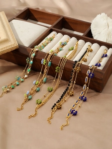 Detail of layered gold floral bracelets with colorful beads in a wooden jewelry box