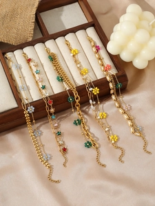 Detail view of five 18K gold-plated stainless steel bracelets with colorful floral charms