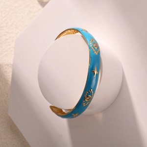 Detailansicht der himmelblauen Emaille-Armspange mit goldenen Sternen und Augen-Motiv