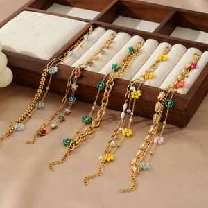 Detail of layered 18K gold-plated stainless steel bracelets with colorful charms