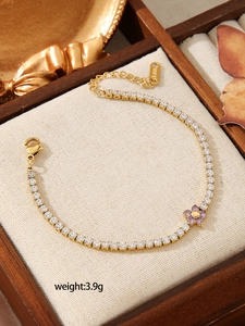 Detail of gold stainless steel tennis bracelet with purple flower charm and square zircons