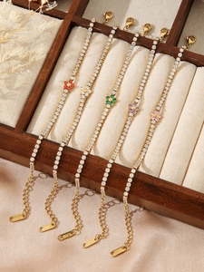 Detailed macro view of five gold tennis bracelets with colorful flower charms and S.STEEL tags