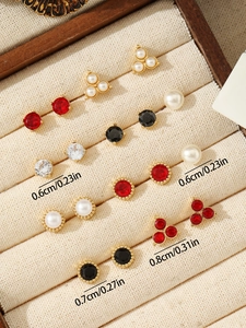Detail view of 12 pairs of gold-plated stud earrings with pearls and crystals in a velvet box