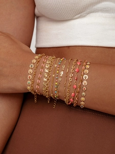 Dettaglio di bracciali boho dorati multistrato con ciondoli a cuore e pendenti a conchiglia