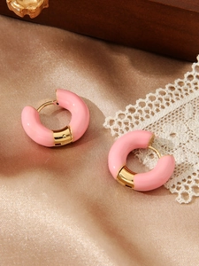 Detail van roze emaille oorringen met 18k goudlaagje op een luxe satijnen achtergrond