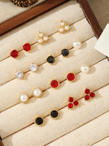 Collection of faux pearl and zircon stud earrings in a wooden jewelry display case