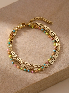 Dettaglio del bracciale dorato multistrato con perline colorate e ciondoli a pesce