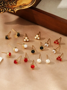 Detailed view of assorted pearl and zircon stud earrings on elegant silk fabric