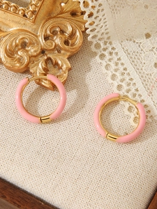 Macro-opname van roze emaille oorbellen met 18k gouden plating op een witte ondergrond