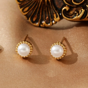 Vintage style round pearl earrings with gold beaded milgrain edges on silk background