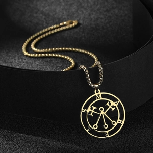 Macro shot of gold Sigil of Marbas pendant with box chain on elegant black background