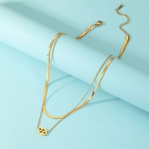 Detail of gold double-layer necklace with Cancer zodiac pendant and lobster clasp