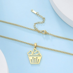 Detail view of golden stainless steel necklace with cupcake pendant on display stand