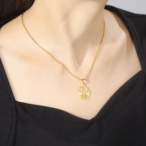 Close-up of a gold stainless steel cupcake pendant necklace worn on a person