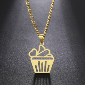 Detail of a hollow cartoon cupcake pendant in gold stainless steel on a black surface