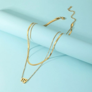 Detail view of a layered gold stainless steel necklace featuring a Virgo zodiac pendant