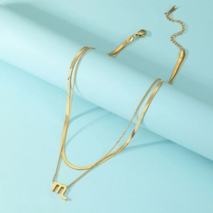 Detail view of double-layer gold Scorpio pendant necklace on a blue pedestal display