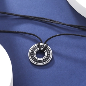 Dettaglio macro del ciondolo a cerchio con rune vichinghe su collana in corda nera